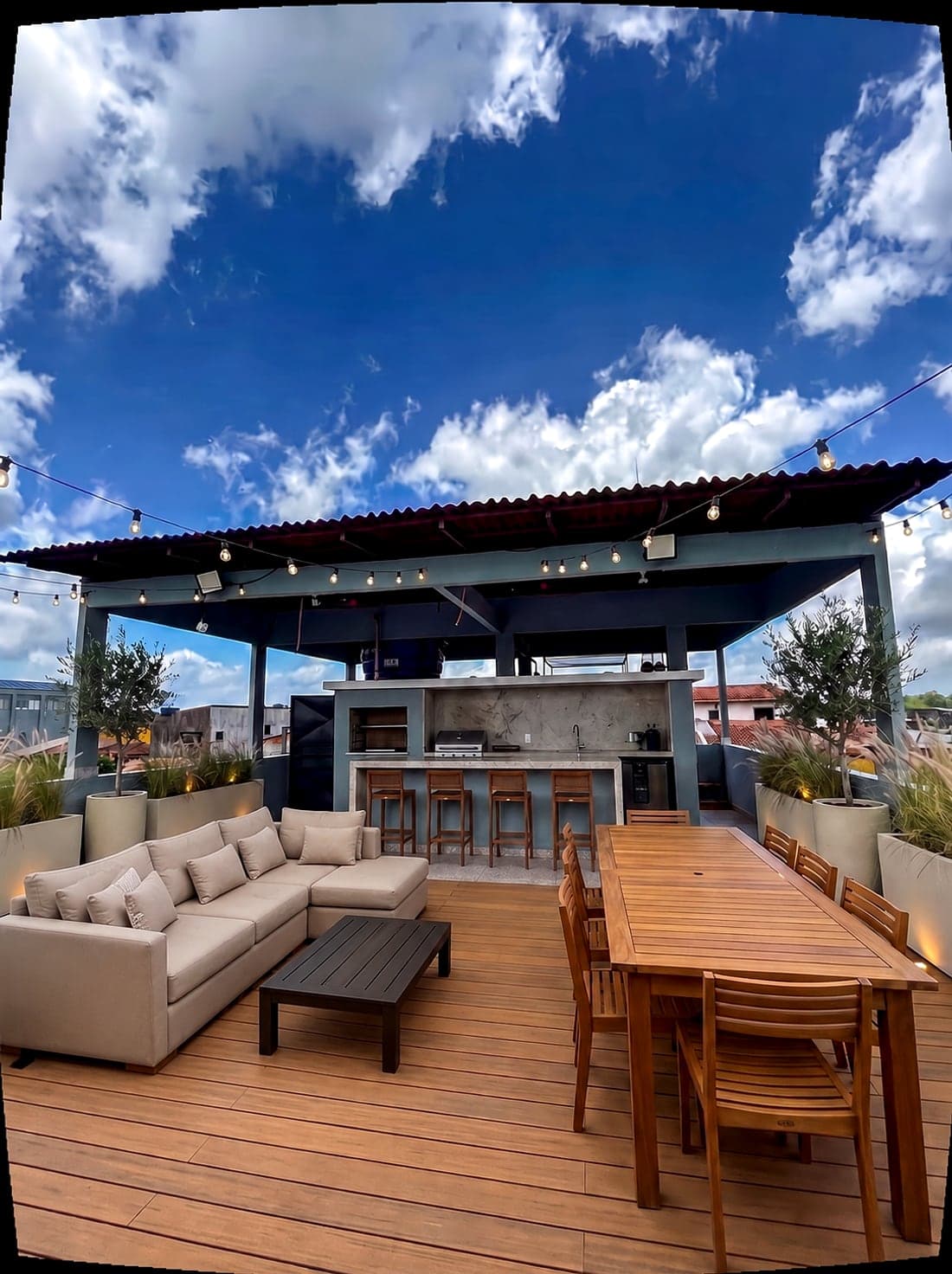 Sugestão de ocupação da cobertura: o balcão vira cozinha externa com bancada de pedra e banquetas, com deck, estar e mesa de jantar sob a pérgola.